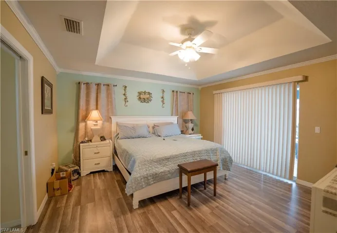 Master bedroom w/tray ceiling & dark vinyl flooring; double sliding glass doors to the lanai