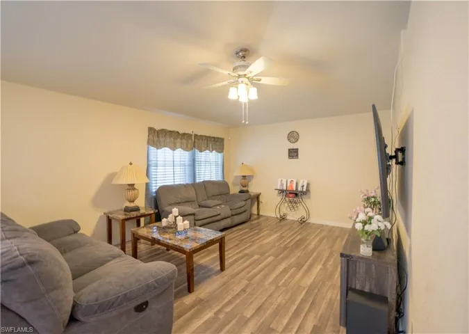Living room w/dark vinyl flooring & ceiling fan