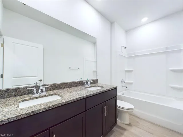 Full bathroom with wood-type flooring, toilet,  shower combination, and vanity
