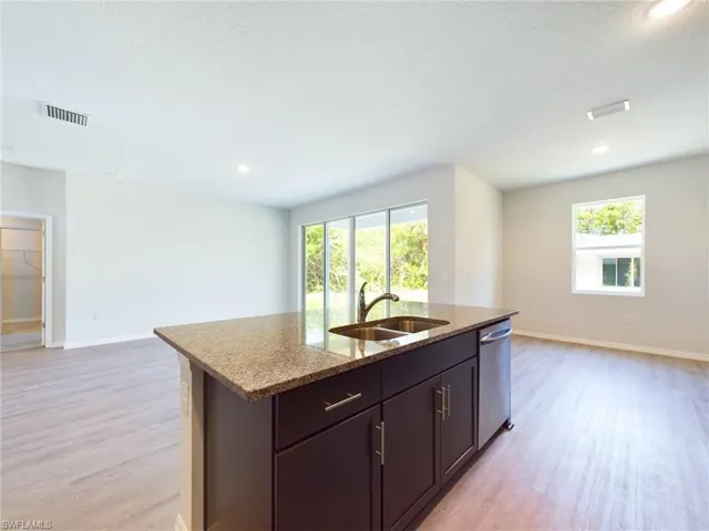 Kitchen with light wood-type flooring, plenty of natural light, sink, and stainless steel dishwasher
