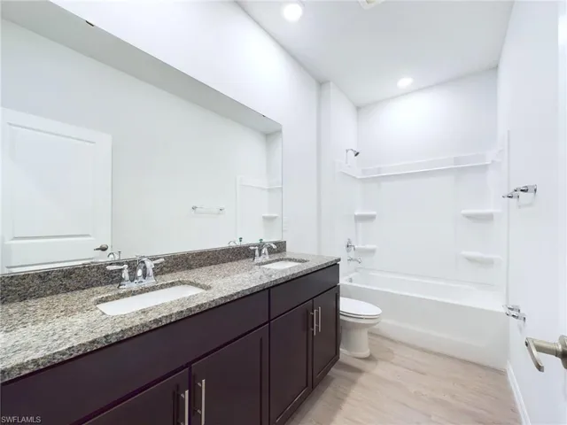Full bathroom with vanity, toilet, bathtub / shower combination, and hardwood / wood-style flooring