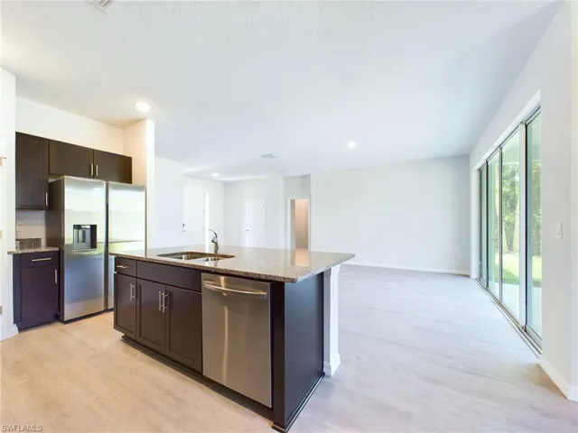 Kitchen with appliances with stainless steel finishes, light hardwood / wood-style flooring, sink, and an island with sink