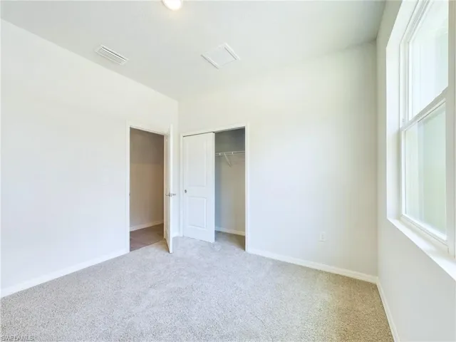 Unfurnished bedroom with light carpet and a closet