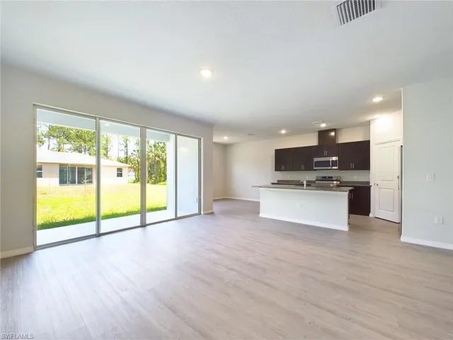 Kitchen with appliances with stainless steel finishes, light hardwood / wood-style flooring, a center island with sink, and sink