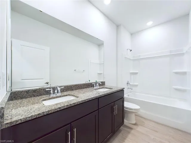 Full bathroom with vanity, toilet, shower / tub combination, and wood-type flooring
