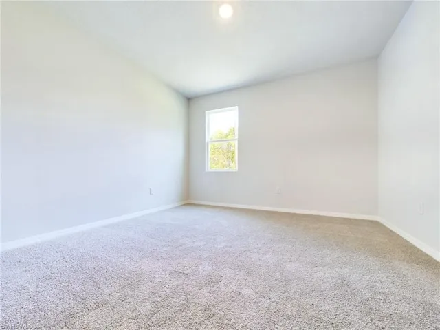 Empty room with vaulted ceiling and carpet flooring