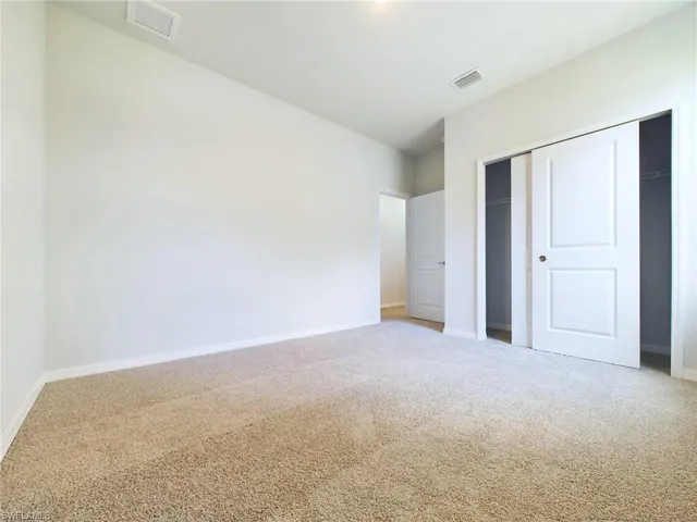 Unfurnished bedroom featuring a closet and light carpet