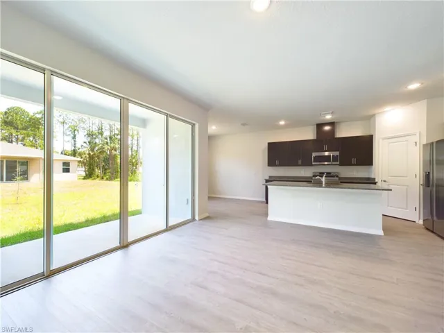 Kitchen featuring sink, stainless steel appliances, an island with sink, and light hardwood / wood-style flooring