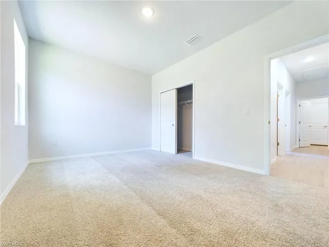 Unfurnished bedroom with light colored carpet and a closet