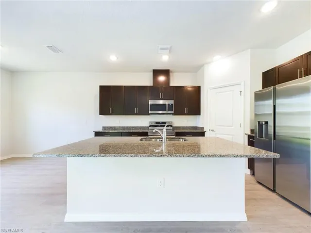 Kitchen featuring a kitchen island with sink, appliances with stainless steel finishes, and light hardwood / wood-style floors