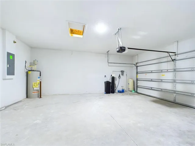 Garage with electric panel, a garage door opener, and water heater