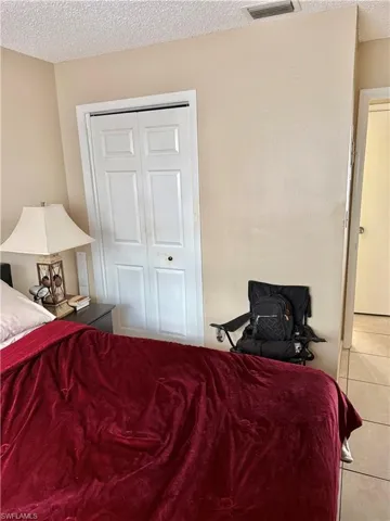 Bedroom with a textured ceiling, tile patterned flooring, and a closet