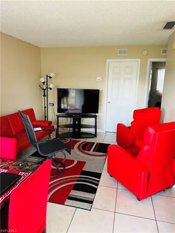 Living room with light tile patterned flooring and a textured ceiling