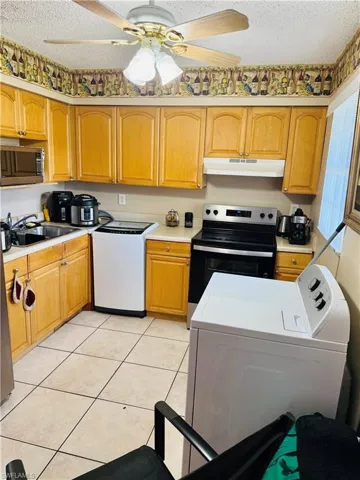 Kitchen with washer / clothes dryer, a ceiling fan, stainless steel appliances, light countertops, and light tile patterned floors