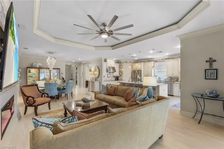 Open-concept living area with wood-finish flooring, tray ceiling, and a built-in fireplace
