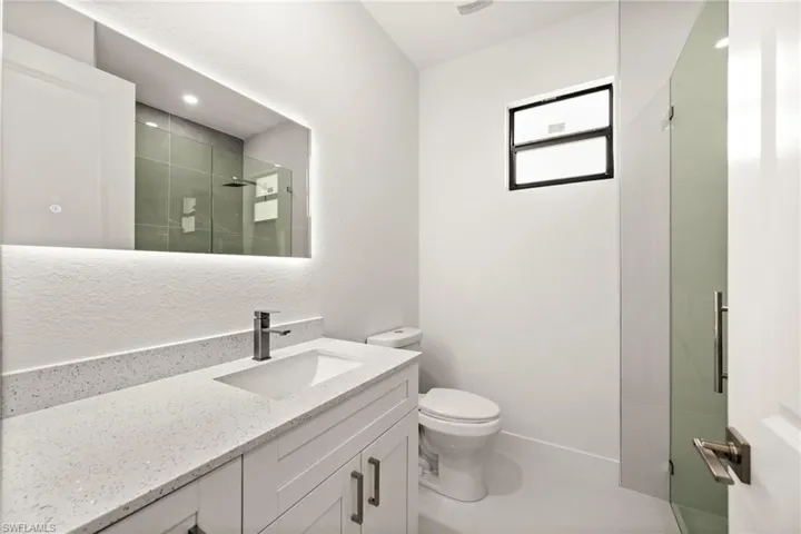 Full bath featuring vanity, a stall shower, and a textured wall