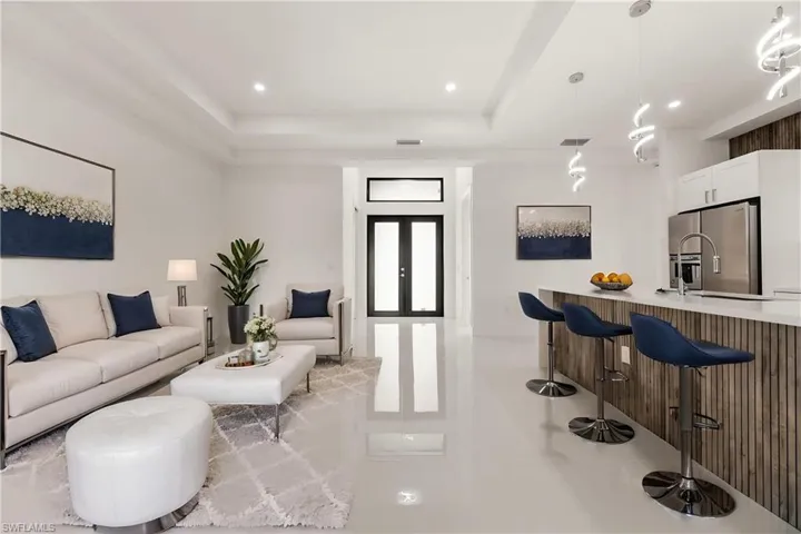 Living area with french doors, light tile patterned floors, a tray ceiling, and recessed lighting