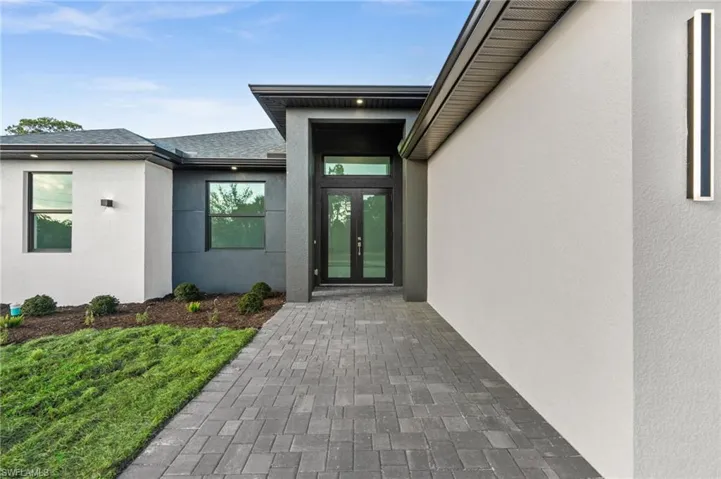 Entrance to property featuring stucco siding, french doors, and roof with shingles