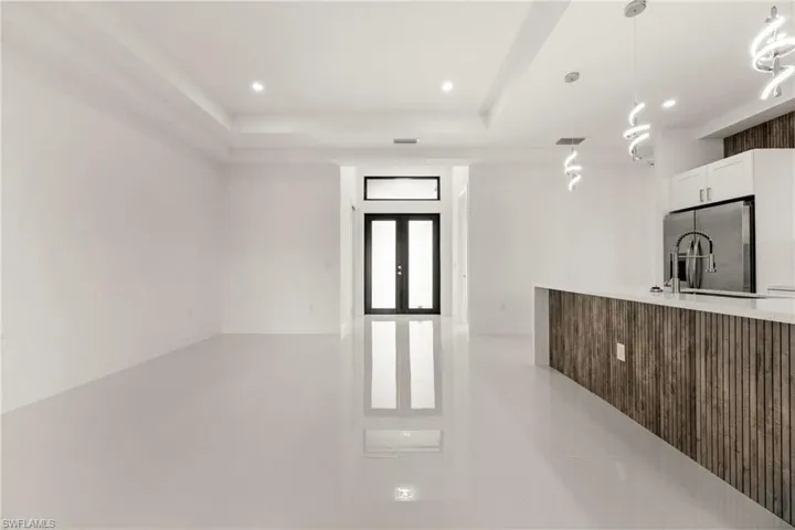 Kitchen with stainless steel fridge with ice dispenser, french doors, pendant lighting, white cabinets, and light stone counters