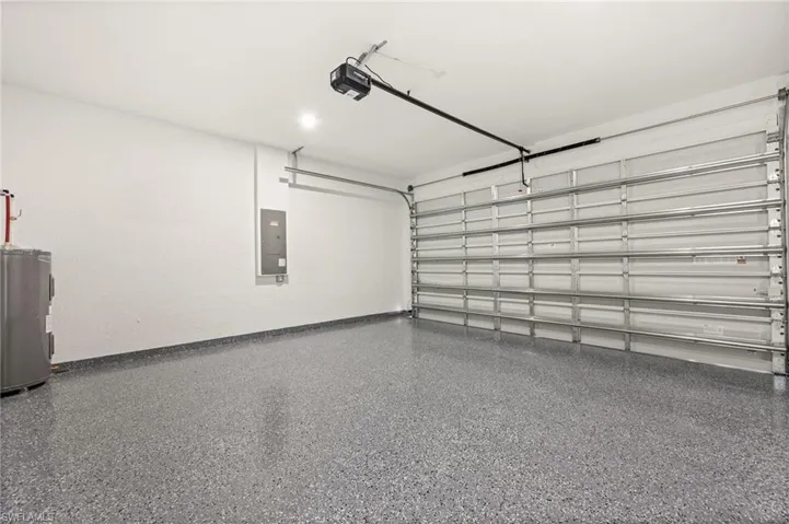 Garage with water heater, electric panel, and a garage door opener