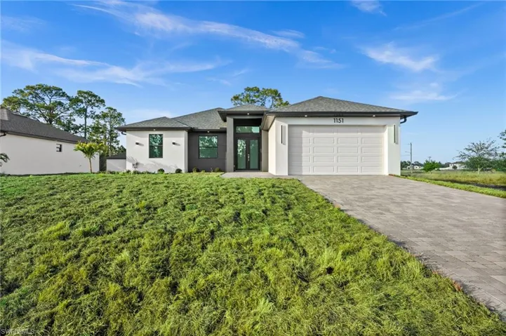 Prairie-style house featuring stucco siding, decorative driveway, and a garage