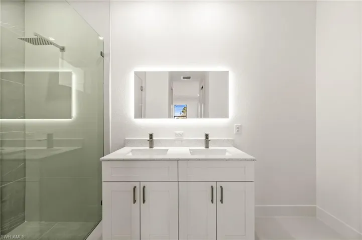 Bathroom featuring double vanity, a stall shower, and a textured wall