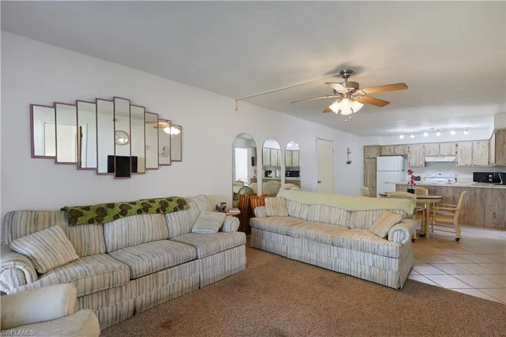Living area featuring light tile patterned flooring, light colored carpet, and ceiling fan