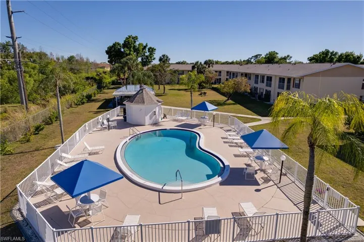 Community pool with a patio area and a grill