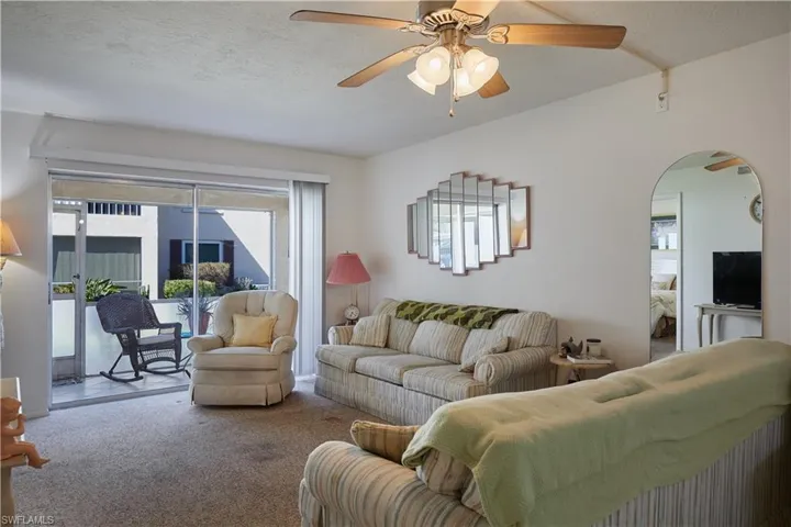 Living room with a ceiling fan, plenty of natural light, a textured ceiling, and carpet flooring