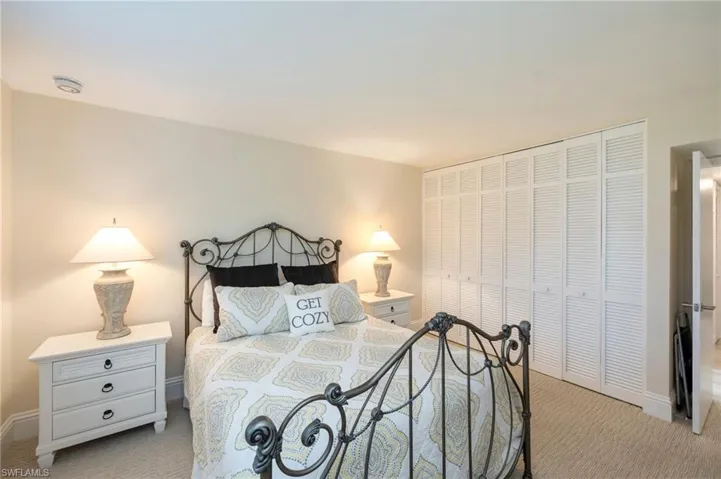 This room features light-colored walls, carpeted flooring, and white louvered bifold closet doors