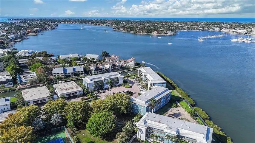 Aerial view of the property and surrounding waterway, showcasing several low-rise buildings and lush green landscaping