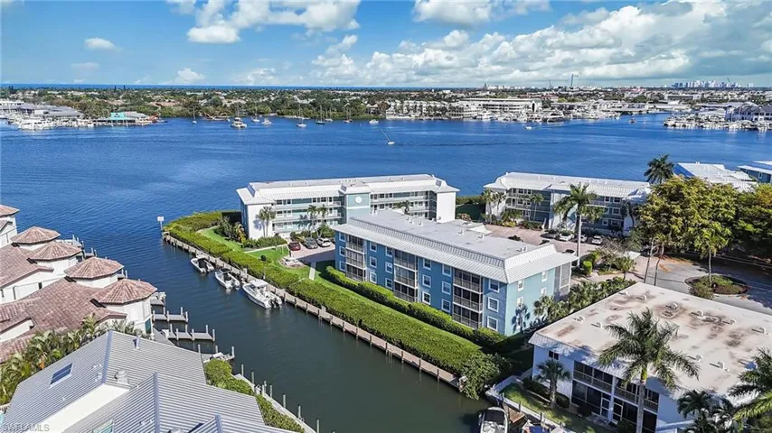 Aerial view showcasing properties situated along a canal, with a wide waterway and distant cityscape in the background