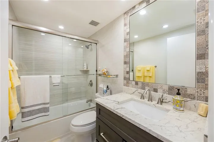 Bathroom featuring a vanity with a light-colored countertop, an undermount sink, and a framed mirror