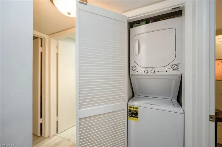 Dedicated laundry closet featuring a stacked washer and dryer unit with louvered bifold doors