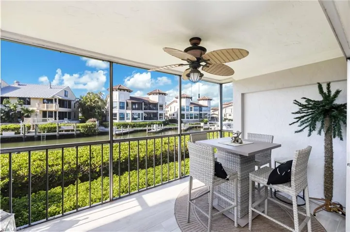 Screened-in balcony with a ceiling fan, offering views of a canal and other properties