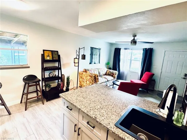 Kitchen featuring open shelves, light stone countertops, white cabinets, and light wood finished floors