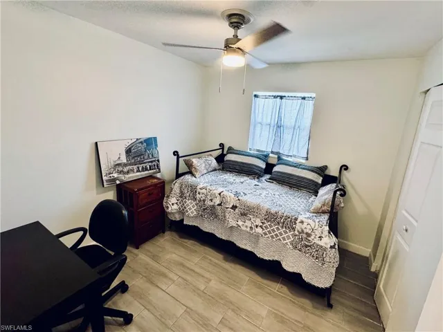 Bedroom featuring light wood-style flooring, a textured ceiling, ceiling fan, and an office area