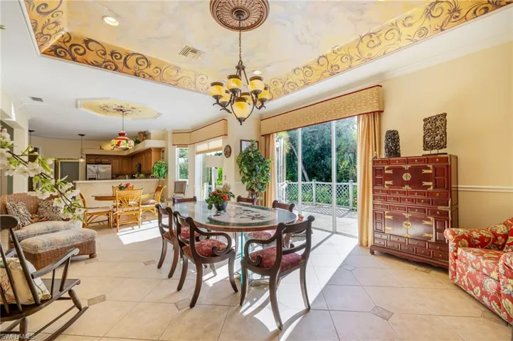 Dining area with a raised ceiling, light tile patterned floors, and crown molding