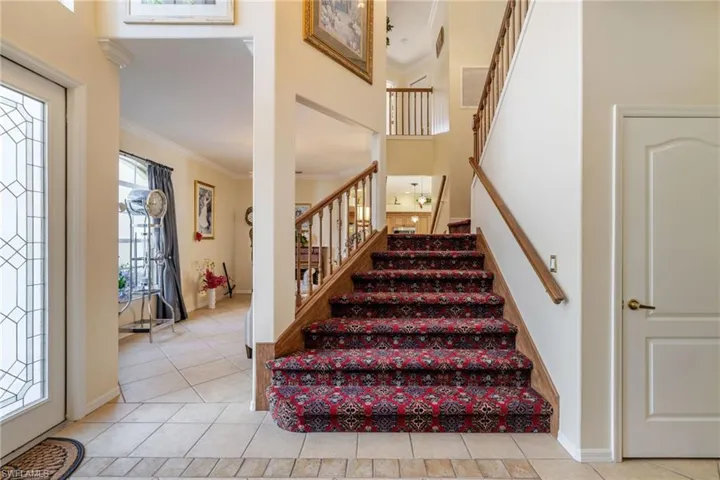 Stairway with crown molding, tile patterned flooring, and a high ceiling