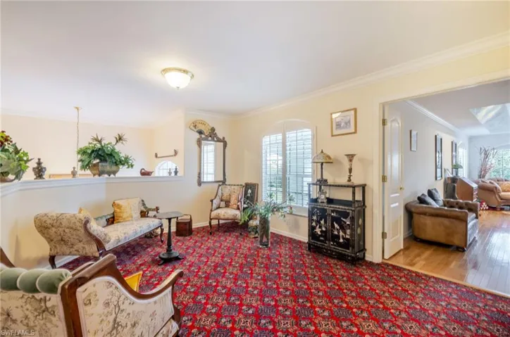 Living area with crown molding, carpet flooring, and wood finished floors