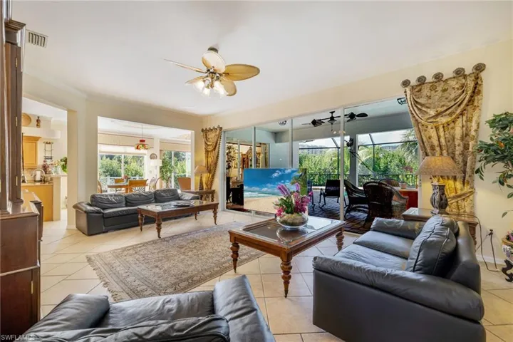 Living area with light tile patterned flooring, a sunroom, healthy amount of natural light, and crown molding