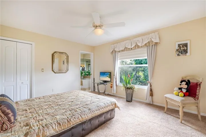Carpeted bedroom featuring ensuite bath, a closet, and a ceiling fan