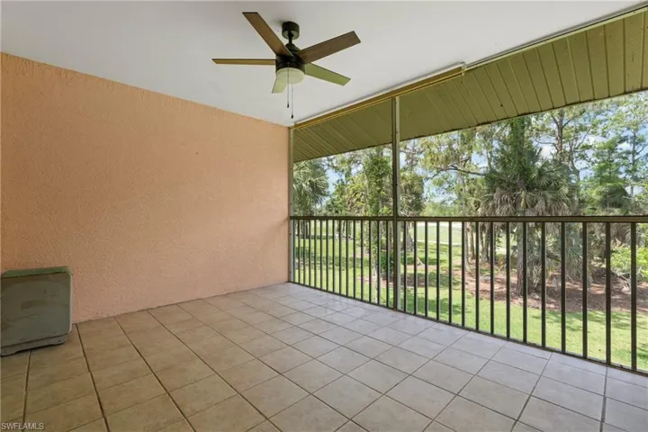 Screened outdoor living area featuring a tile floor, textured wall, and a ceiling fan
