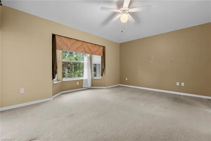Spacious room featuring neutral carpeting and a wide bay window with a decorative valance and natural light