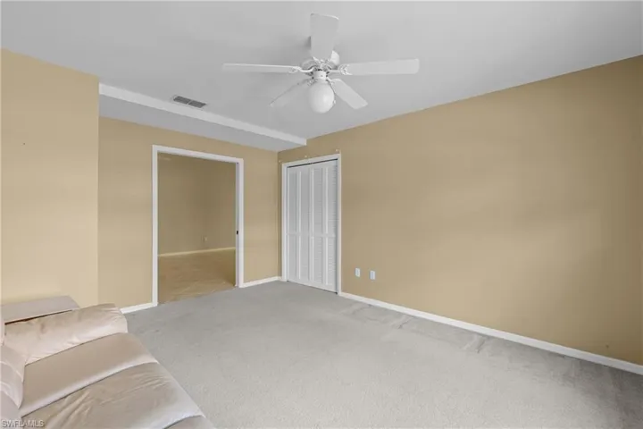 Spacious interior room featuring light beige walls and light gray carpet flooring