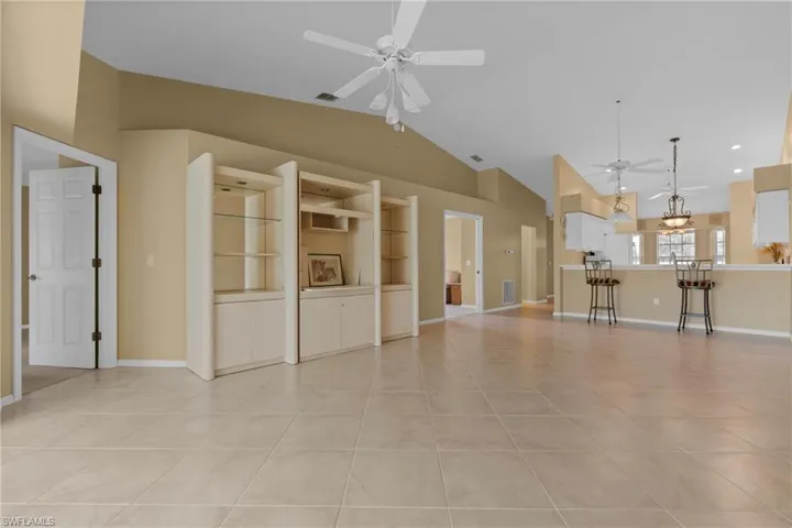 Spacious open-concept interior featuring large format tile flooring, vaulted ceilings, and multiple ceiling fans