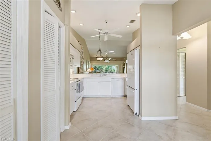 Kitchen with white cabinets, recessed lighting, light countertops, white appliances, and decorative light fixtures