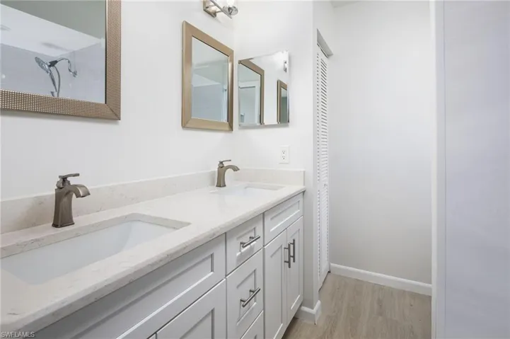Primary bath featuring double sink quartz vanity and light wood-type flooring