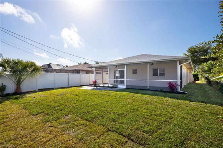 Back of house with a sunroom and a fenced, newly landscaped backyard,