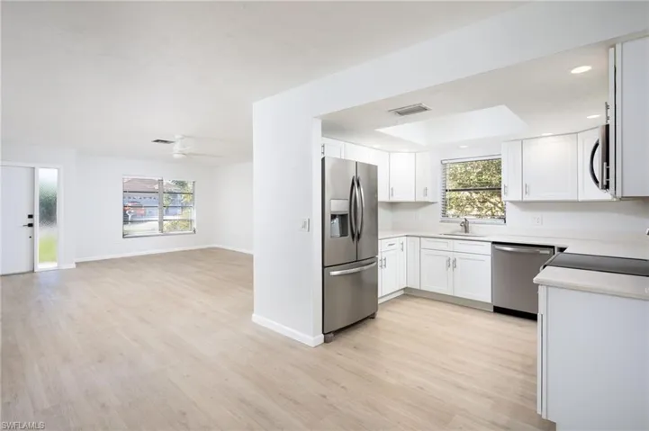 Kitchen featuring stainless steel appliances, white cabinetry, light wood-style floors, plenty of natural light, and recessed lighting